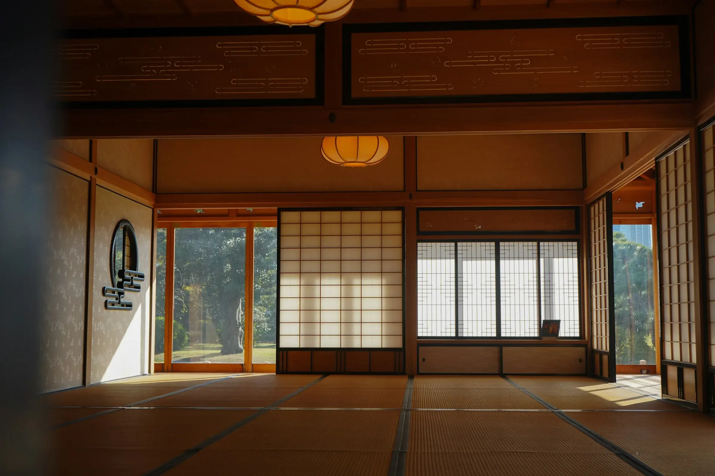 A large tatami room with shoji screens, the dark edging of each mat drawing lines across the floor